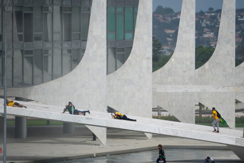 Invasores são vistos deitados na rampa do Palácio do Planalto durante ato criminoso em Brasília — Foto: Eraldo Peres/AP